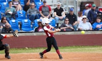 a softball player swings at a ball during a game